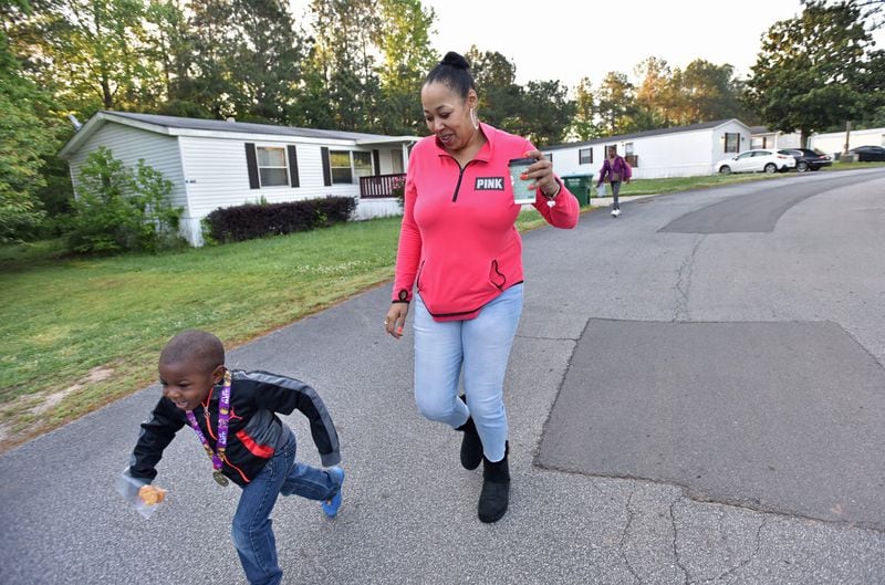 Jayceon, 4, races his mother Priscilla Vetaw to a school bus stop in Smoke Creek. Vetaw moved there from a residential motel so her children could live in a safe neighborhood. HYOSUB SHIN / HSHIN@AJC.COM