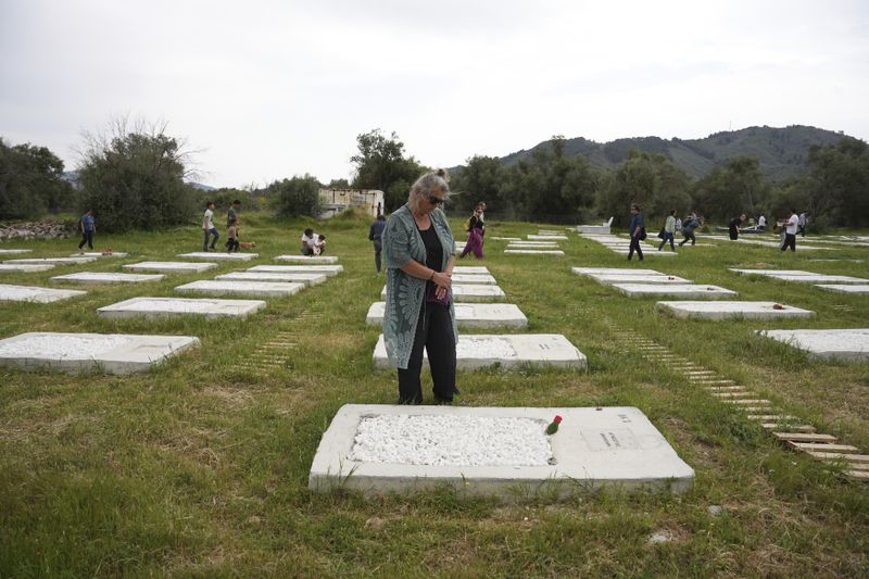 People visit the cemetery at Kato Tritos village on the northeastern Aegean Sea island of Lesbos, Greece, on Wednesday, April 17, 2024. After years of neglect, a primitive burial ground for refugees who died trying to reach Greece's island of Lesbos has been cleaned up and redesigned to provide a dignified resting place for the dead. (AP Photo/Panagiotis Balaskas)