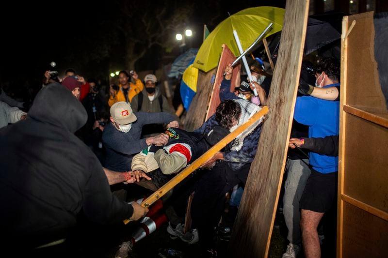 Demonstrators clash at a pro-Palestinian encampment at UCLA early Wednesday, May 1, 2024, in Los Angeles. Dueling groups of protesters have clashed at the University of California, Los Angeles, grappling in fistfights and shoving, kicking and using sticks to beat one another. (AP Photo/Ethan Swope)