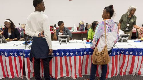 Jeremiah Culver, left, and Quinnayah Durden, right, both seniors at Columbia High School, wait to have their voting paperwork processed in Atlanta, on Monday, October 31, 2016. (DAVID BARNES / DAVID.BARNES@AJC.COM)