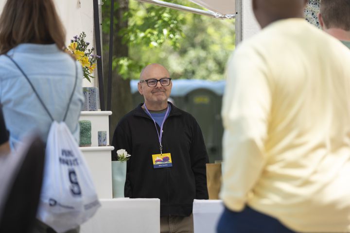 Mike Hamlin of Asheville watches the crowd while working his ceramics booth at the Dogwood Festival in Piedmont Park on Saturday, April 13, 2024.   (Ben Gray / Ben@BenGray.com)
