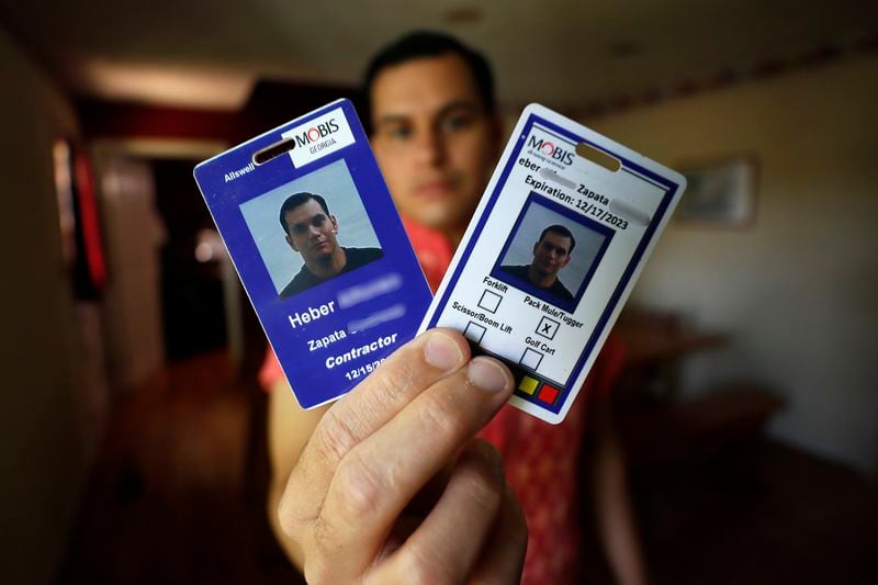 Heber Zapata holds his ID badges from his time working at a nearby Hyundai Mobis plant. His ID notes a job description of "pack mule/tugger." (Miguel Martinez / miguel.martinezjimenez@ajc.com)