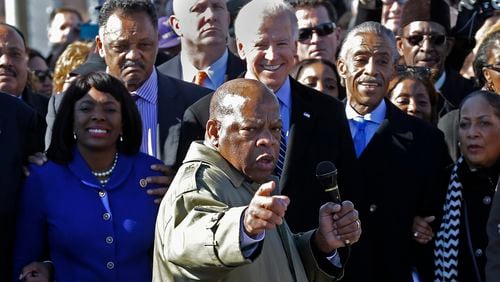 In this March 2013 file photo, U.S. Rep. John Lewis, D-Ga., points to where he and others were beaten 48 years ago when they tried to cross the Edmund Pettus Bridge during a civil rights march in Selma, Ala. At rear is Vice President Joe Biden. At left is U.S. Rep. Terri Sewell, D-Ala.; Jesse Jackson is second from left. (AP Photo/Dave Martin)