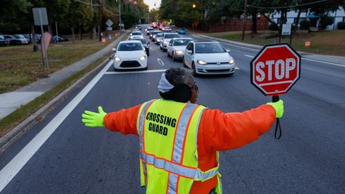 Crossing guard Karen Law stops traffic in Decatur on Tuesday, October 18, 2022. Temperatures are in the 40s Tuesday in Atlanta for the coldest morning the city has seen in six months. (Arvin Temkar / arvin.temkar@ajc.com)