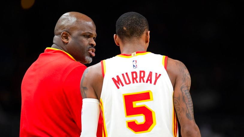 Atlanta Hawks head coach Nate McMillan, left, speaks to guard Dejounte Murray (5) during the second half of an NBA basketball game against the Denver Nuggets, Friday, Dec. 2, 2022, in Atlanta. (AP Photo/Hakim Wright Sr.)