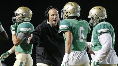 Buford head coach Jess Simpson, center, congratulates defensive back Bryson Richardson (6) and others on a defensive play in the first half of their game against Carrollton at Buford High School November 25, 2016, in Buford, Ga. This is a quarterfinal game in the Class AAAAA high school football playoffs. PHOTO / JASON GETZ